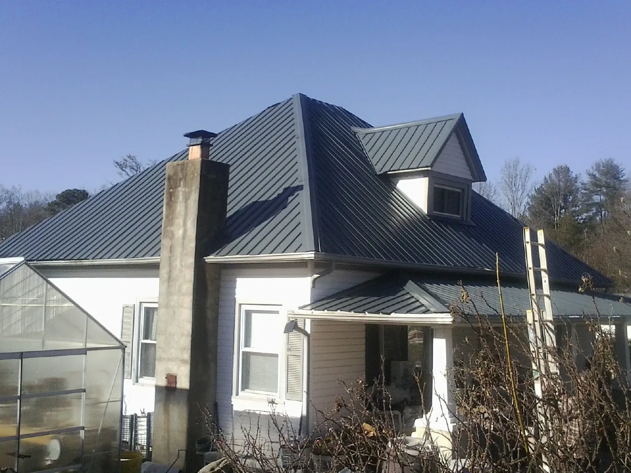 Dark blue standing seam metal roof on a white farmhouse with dormer — Slate & Tile Roof Repair by Roofing Brothers in Hamilton